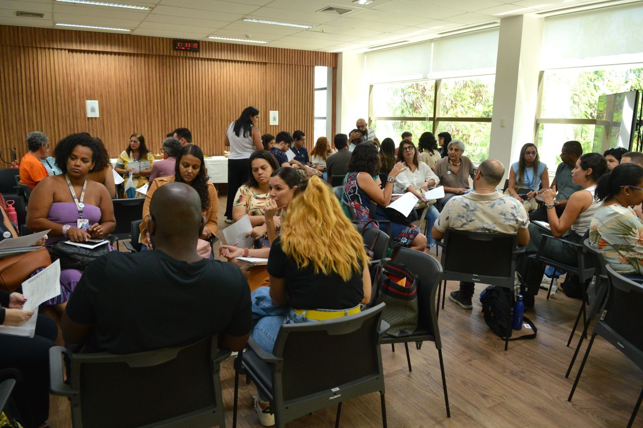 Foto. Plano geral do encontro com grupos reunidos para discussão