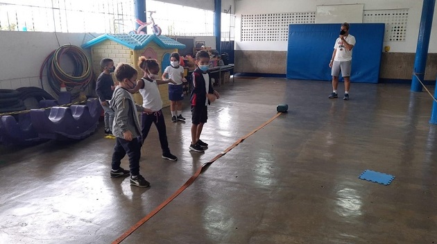 Terra e mar crianças brincam diante de uma fita ao chão no pátio da escola